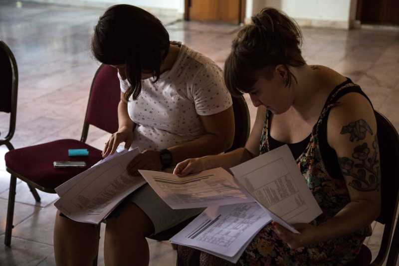 Julianna and another participant are looking carefully session outlines of  different country teams. Julianna and another participant are looking carefully session outlines of different country teams.